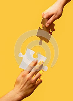 Closeup hands of man connecting jigsaw puzzle. Two hands trying to connect couple puzzle with yellow background. Hand