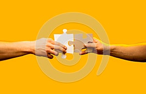 Closeup hands of man connecting jigsaw puzzle. Two hands trying to connect couple puzzle with yellow background. Hand
