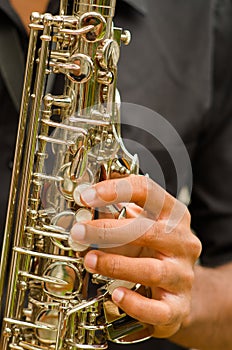 Closeup hands of man wearing dark shirt and playing saxophone