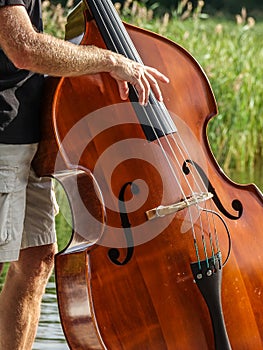 Closeup of hands play on a double bass / contrabass outdoors