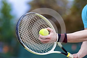 Closeup of Hands of Professional Male tennis Player Holding Raquet and Tennis Ball in Contact.