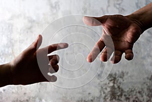 Closeup of hands reaching to touch against a gray background
