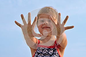 Closeup of hands in the sand, a little girl playing on the beach