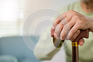 Closeup hands of senior disabled man holding walking stick