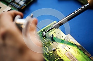 Closeup of hands soldering tin to electronics circuit board