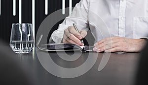 Closeup hands taking notes in planner, planning business appointments. Businessman sitting at desk and writing in