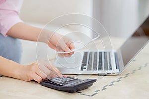 Closeup hands of woman calculating finance household with calculator on desk at home.