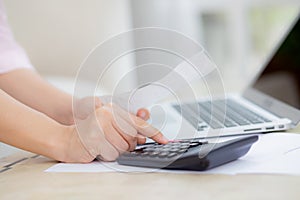 Closeup hands of woman calculating finance household with calculator on desk at home.