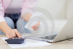 Closeup hands of woman calculating finance household with calculator on desk at home.