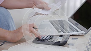 Closeup hands of woman calculating finance household with calculator on desk at home.