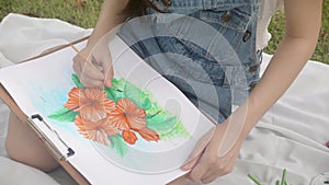 Closeup hands of woman sitting drawing picture with colorful paint brush while leisure in the park on summer.