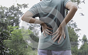 Closeup hands of woman touching her back pain in healthy concept on nature background