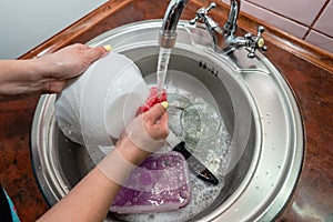 Close up hands of woman washing dishes in kitchen. Cleaning chores