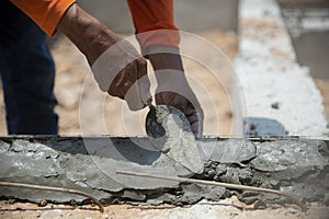 Closeup hands of the workers were plastering cement concrete on the walls with trowel at house construction site