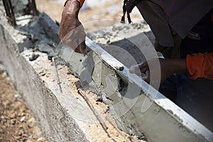 Closeup hands of the workers were plastering cement concrete on the walls with trowel at house construction site