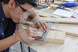 Closeup hands of young asian carpenter measuring on wooden job with try square