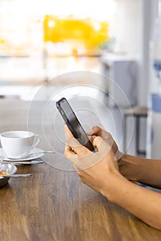 Closeup hands of young asian man working smartphone after eating breakfast drinking coffee