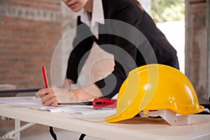 Closeup hands young caucasian architect woman looking laptop and working drawing blueprint for planning building house.