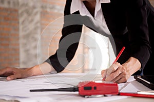 Closeup hands young caucasian architect woman looking laptop and working drawing blueprint for planning building house.