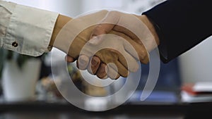 Closeup of handshake on background of office. Good business deal secured partnership with handshake. Two coworkers