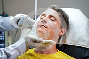 Closeup handsome man having color light therapy to stimulate facial skin