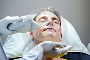 Closeup handsome man having color light therapy to stimulate facial skin