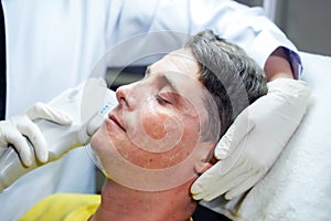 Closeup handsome man having color light therapy to stimulate facial skin