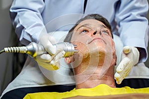 Closeup handsome man having therapy to stimulate facial skin and facial ultrasonic skincare treatment by professional