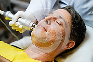 Closeup handsome man having therapy to stimulate facial skin and facial ultrasonic skincare treatment by professional