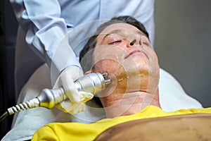 Closeup handsome man having therapy to stimulate facial skin and facial ultrasonic skincare treatment by professional