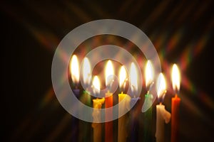 Closeup of Hanukkah menorah, or hanukkiah for Jewish holiday Hanukkah. Nine colored candles with star filter.