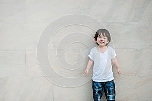 Closeup happy asian kid with smile face on marble stone wall textured background with copy space