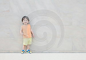Closeup happy asian kid with smile face on marble stone wall textured background with copy space