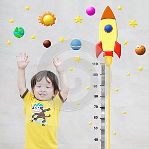 Closeup happy asian kid stand for measure height with cute cartoon at the marble stone wall textured background in growth of kid c