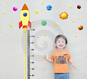 Closeup happy asian kid stand for measure height with cute cartoon at the marble stone wall textured background in growth of kid c