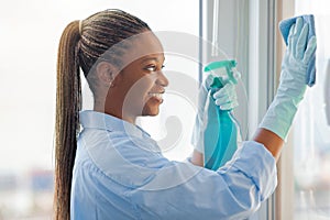Closeup of happy black woman cleaning windows