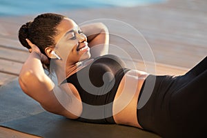 Closeup of happy black woman working on abs outdoors