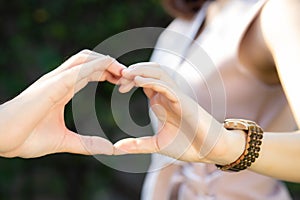 Closeup of happy couple fun making gesture heart shape with hand outdoor together