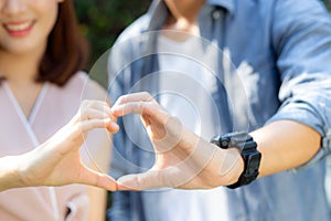 Closeup of happy couple fun making gesture heart shape with hand outdoor together