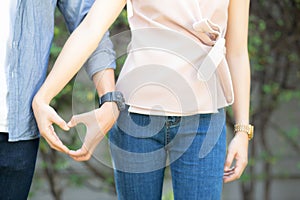 Closeup of happy couple fun making gesture heart shape with hand outdoor together