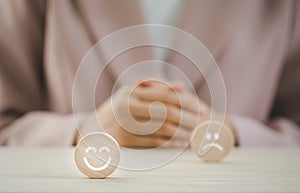 Closeup happy face on round wood piece in front of sad one with businesswoman on background