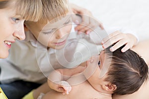 Closeup of happy family. Joyful mom and her kid son looking at newborn baby.