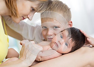 Closeup of happy family. Joyful mom, her kid son and newborn baby together