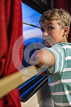 Closeup happy male kid looking window smiling travel by train at comfortable luxury railway carriage