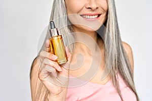 Closeup of happy mid age Asian woman hand holding hair and skin care oil serum.