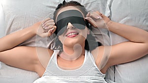 Closeup happy morning woman stretching awaking in comfortable bed wearing black sleeping mask
