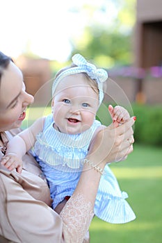 Closeup happy mother holding little female child in blue dress.