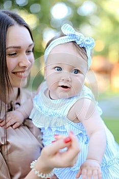 Closeup happy mother holding little female child in blue dress.