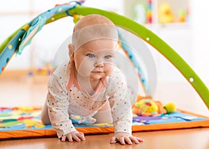 Closeup of happy seven months baby girl crawling on colorful playmat photo