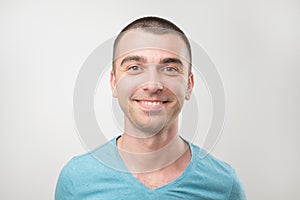 Closeup of happy smiling guy in blue shirt looking at camera